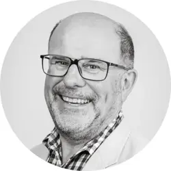 David Bowen. A white man in his 60s. David wears glasses, a check shirt and a light coloured jacket.
